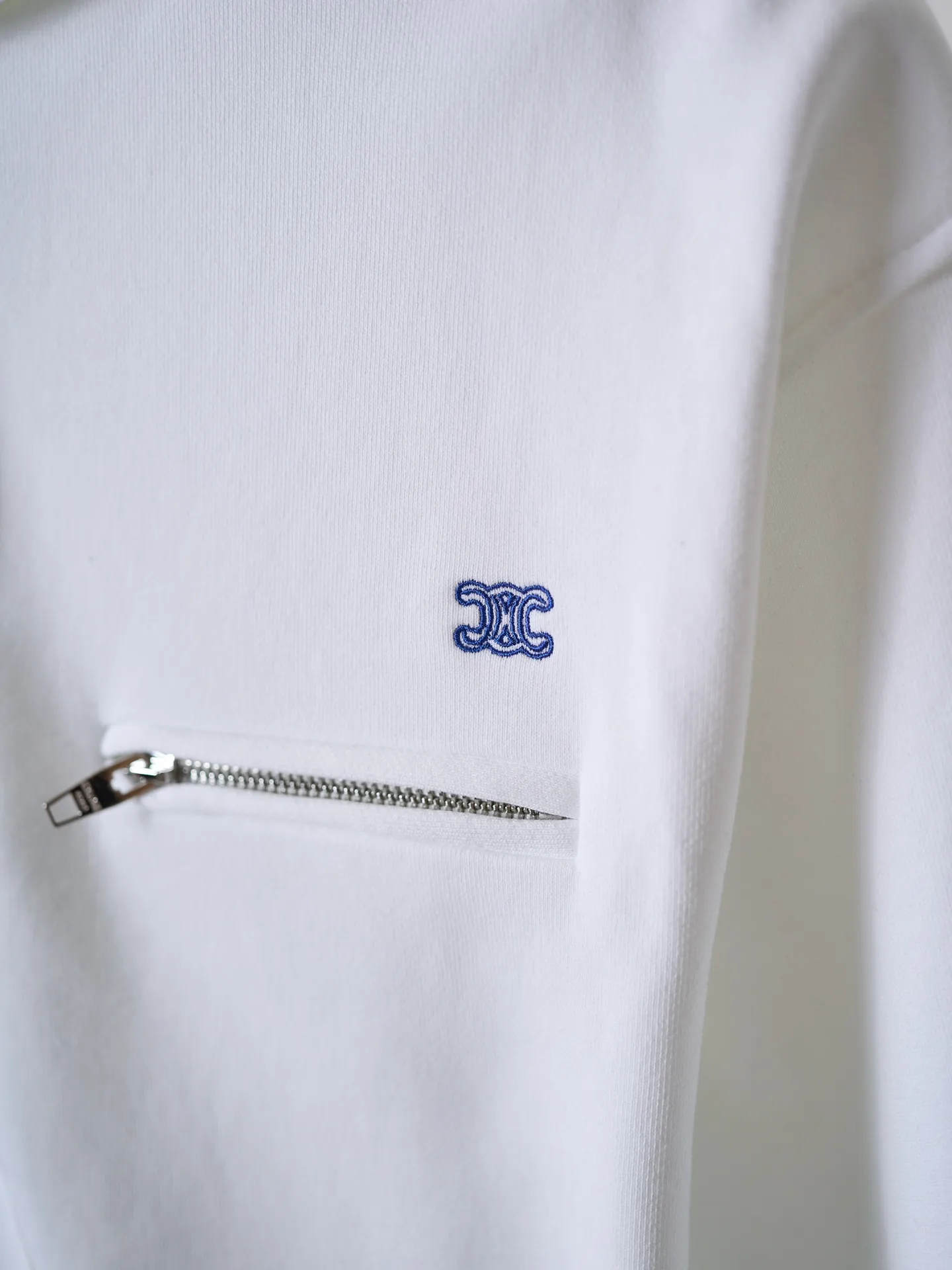 [Real auction] Celine/Celine logo embroidered zipper jacket (women's style) [In Stock] S M L custom-made light oxygen cotton-feel fleece knit, delicate and smooth, soft and skin-friendly. The body is laid out in clear white, with a soft cotton-like texture and rich layers. The elegant white tone brings a refreshing and clean daily atmosphere. The iconic Celine Arc de Triomphe embroidery is embellished on the chest, which is simple yet memorable. The simple hoodie silhouette sets a refreshing tone, and the two-way metal zipper design is full of texture. The short silhouette with loose, dropped shoulders gently modifies the lines of the shoulders and arms; the drawstring at the hem is adjustable to shape the silhouette as desired, and the short length optimizes body proportions. The simple silhouette carries a lazy atmosphere, and the relaxed outfit reveals the French girlish attitude. 1. Imported machine embroidery technology uses advanced computer control systems and precision mechanical components to precisely create the iconic TRIOMPHE logo embroidery, with smooth and delicate lines and a full sense of sophistication. 2. Fermentation washing treatment: The fabrics have been fermentation washing, which makes the hand feel and texture better, is not easy to deform, shrink, and fade, and maintains long-term beauty and loose fit.